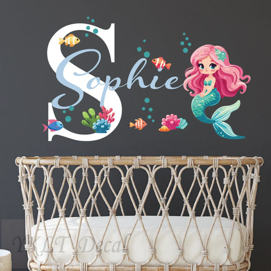 Personalized mermaid wall decal with name Sophie above a crib, featuring colorful sea creatures, by YKLT Decals