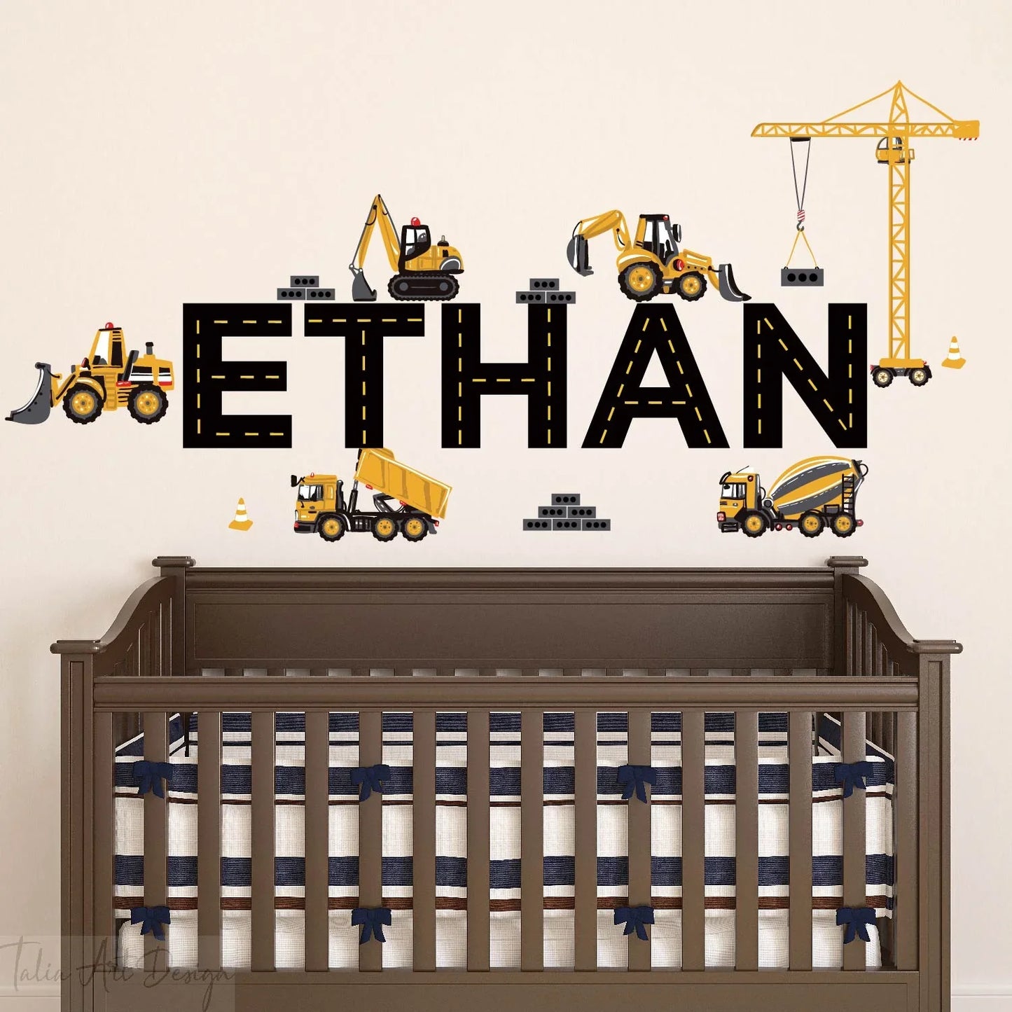 Construction vehicle wall decals with personalized 'Ethan' name above a crib in a nursery.