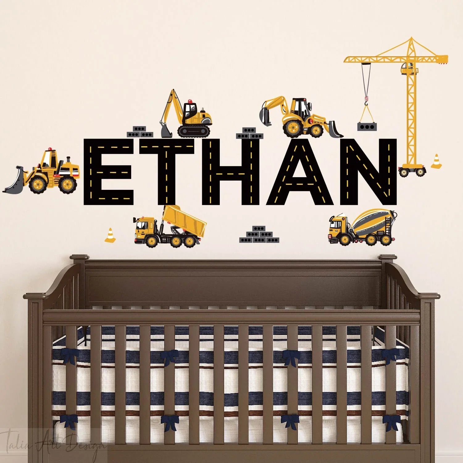 Construction vehicle wall decals with personalized 'Ethan' name above a crib in a nursery.